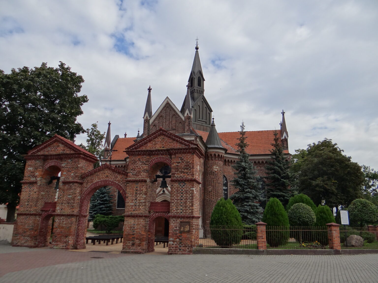 Gotycki kościół świętego Andrzeja w konińskich Gosławicach z ceglaną bramą i dzwonnicą