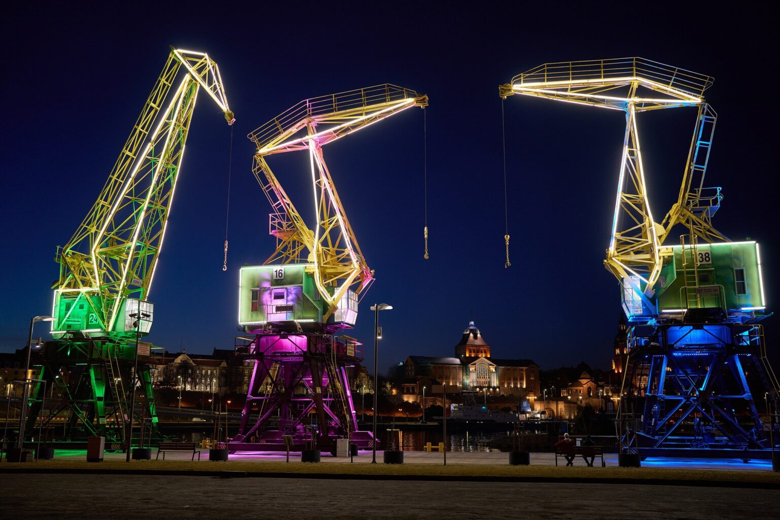 Podświetlone zabytkowe dźwigi portowe na Łasztowni nocą; reklama Google Ads dla firm ze Szczecina