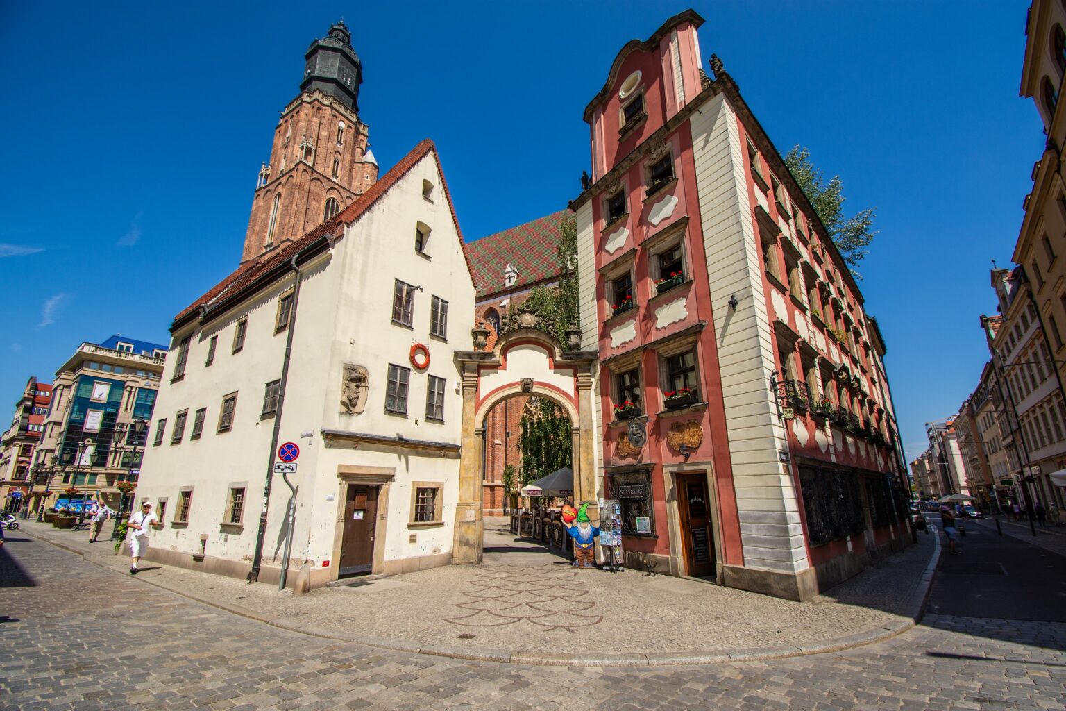 Para kamieniczek Jaś i Małgosia we Wrocławiu z bramą, głębokie błękitne niebo; reklamy Google Ads dla firm z Wrocławia